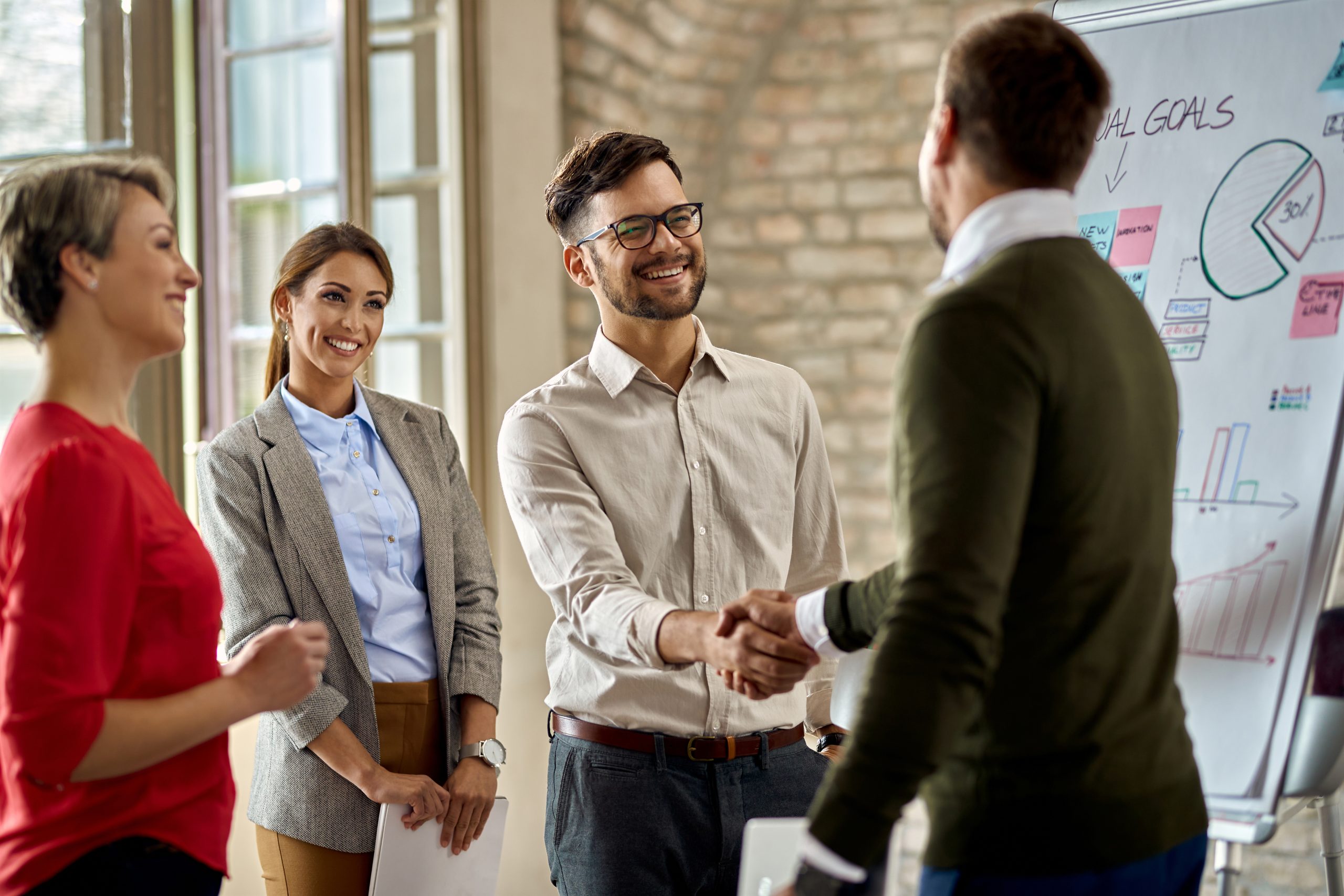 happy coworkes shaking hands after business presentation office scaled